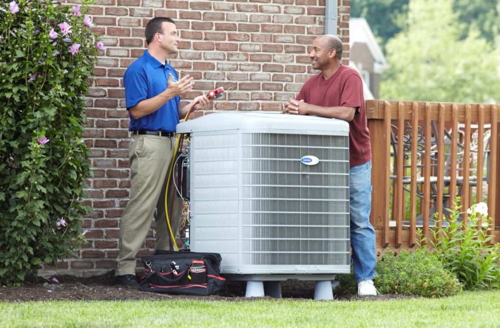 two men talking outside by an air conditioner unit